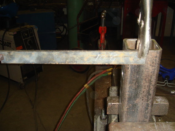 Metal bar with '10 1/4' written on it, clamped to a square metal tube