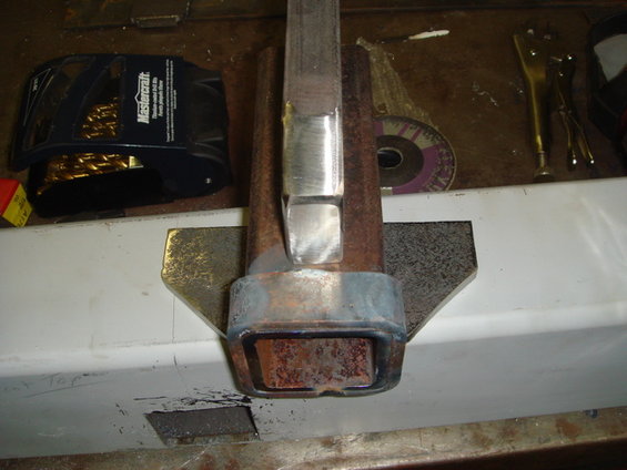 Metal tubing being welded in a vise, with a grinding disc and safety glasses nearby