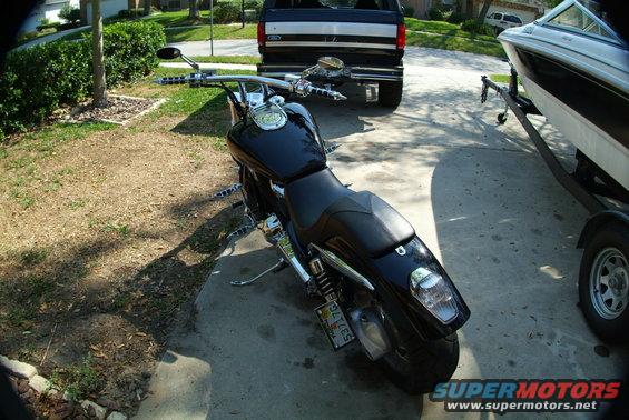 Rear view of a black motorcycle parked in front of a 1995 Ford Bronco and a boat on a trailer