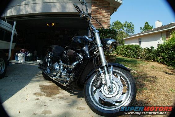 Black cruiser motorcycle parked in a driveway in front of a garage