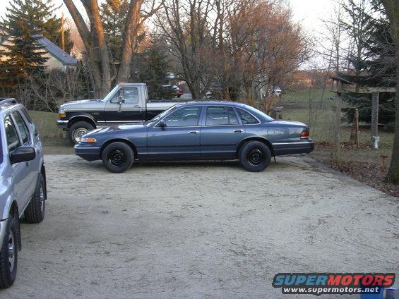 Blue 1996 Ford Crown Victoria sedan parked next to a pickup truck
