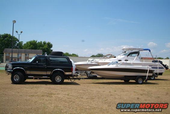 Black 1995 Ford Bronco side view, towing two boats on trailers