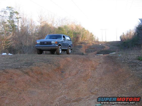 Blue 1989 Ford Bronco parked on a dirt embankment