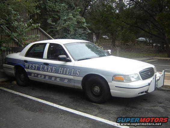 White police car with blue stripes and "WEST LAKE HILLS POLICE" text, parked in a lot