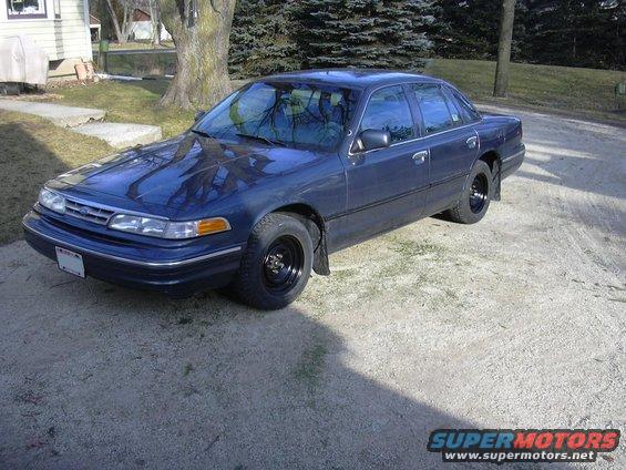 Dark blue sedan parked on a gravel driveway. It has black wheels and mud flaps
