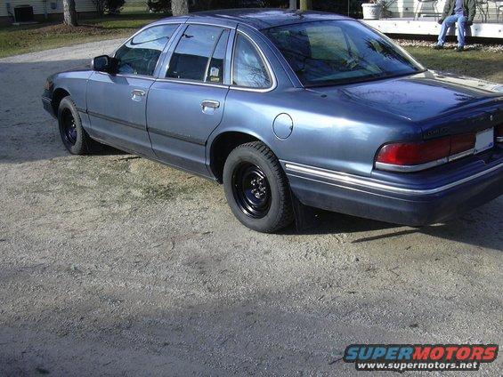 Blue sedan with black steel wheels parked on gravel