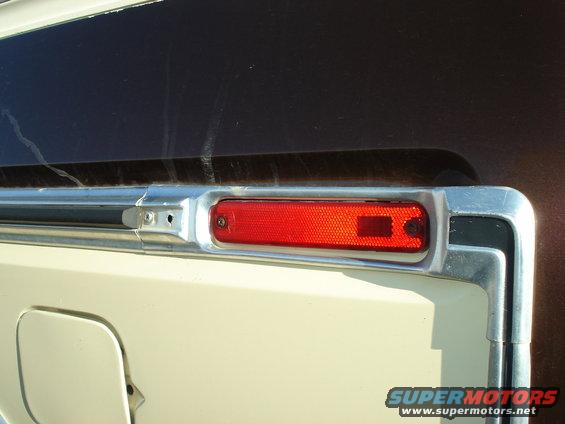 Close-up of a red rectangular marker light with chrome trim on a vehicle