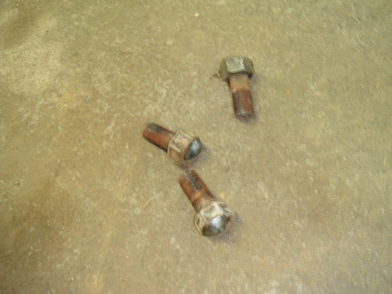 Three rusty bolts on a concrete surface