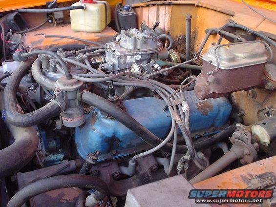 Engine bay with carburetor, brake fluid reservoir, and hoses visible