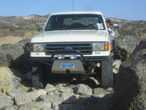 White Ford Bronco navigating rocky terrain, front view