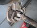 1991 Ford Bronco - This image shows a heavily rusted front axle assembly, likely from an older vehicle, with visible brake components and some stamped marking…