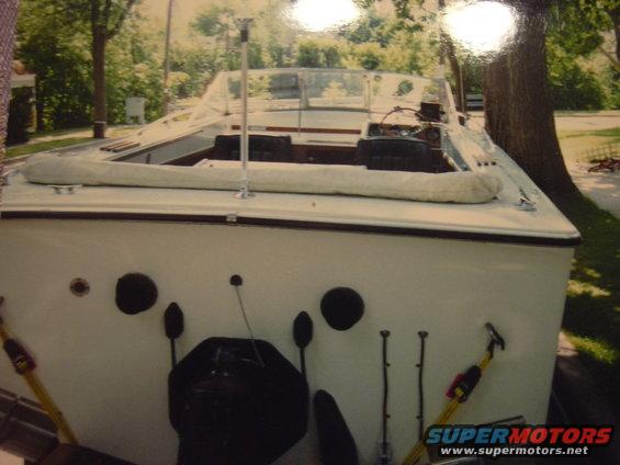 White boat with a tan interior and windshield, parked near trees