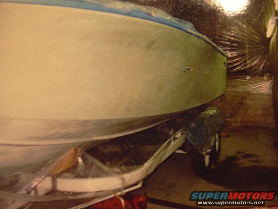 Boat on a trailer, covered, with blue trim, side view