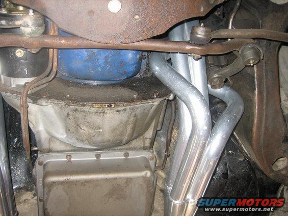 Underside view of a vehicle's transmission pan, oil pan, and exhaust headers