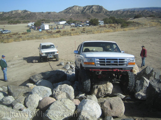 Ford Bronco climbing over rocks, another SUV in background