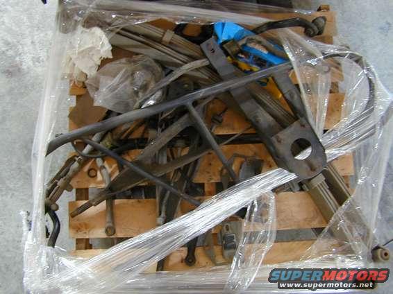 Metal vehicle parts wrapped in plastic on a wooden pallet