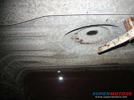 Underside of a vehicle's frame with some rust and a bolt visible