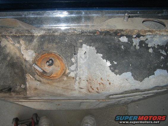 Rusty gas tank with fuel filler neck and mounting bolts visible
