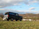 1992 Ford Bronco - This 1992 Ford Bronco is seen from a 3/4 front angle, parked on a grassy incline under a partly cloudy sky.
