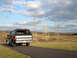 1992 Ford Bronco - 1992 Ford Bronco seen from the rear on a road with power line towers in the distance.