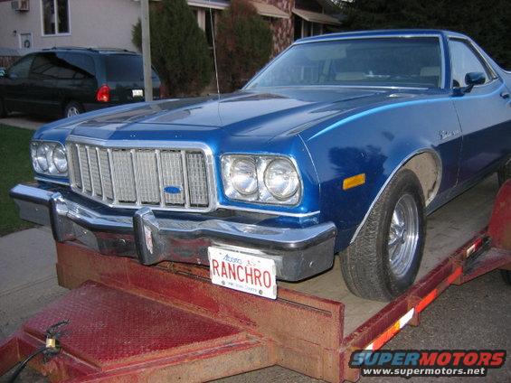 Blue 1976 Ford Ranchero front view on a red trailer, license plate reads 'RANCHO'