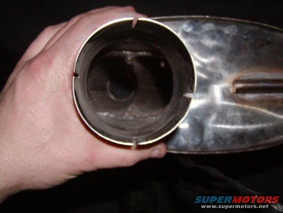 Hand holding a chrome exhaust pipe with internal baffles visible