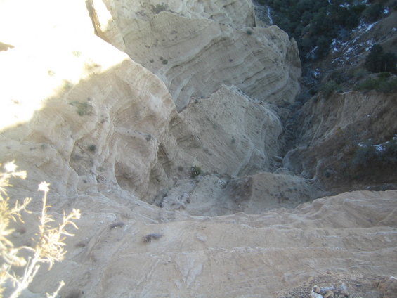 Overhead view of a dry, rocky canyon with layered rock formations and sparse vegetation