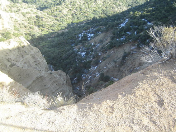 Dry, dusty canyon with sparse vegetation and patches of snow on a hillside