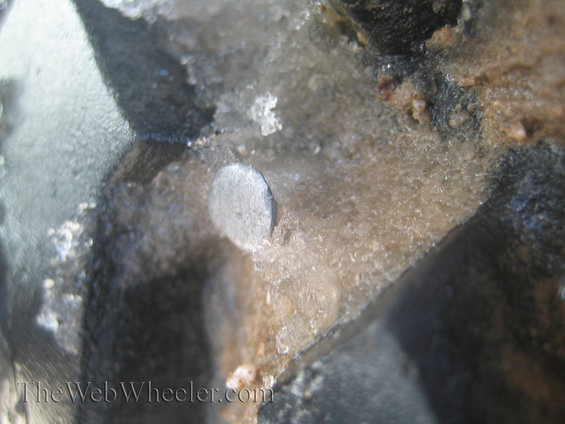 Close-up of a metal pin embedded in ice and dirt