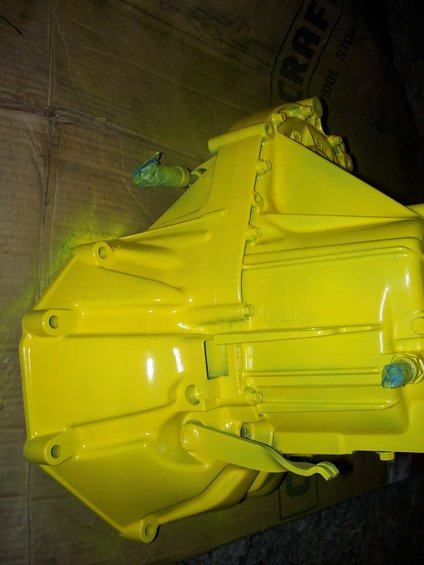 Yellow painted transmission housing with blue tape on fittings