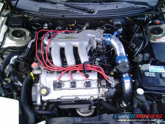 1997 Ford Probe engine bay with V6 intake manifold, red spark plug wires, and blue intake piping