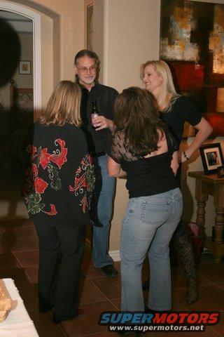 People gathered indoors, one man holds a beer bottle