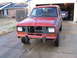 1984 Ford Bronco II - Front view of a red 1984 Ford Bronco II undergoing repairs, with its grille and bumper removed.