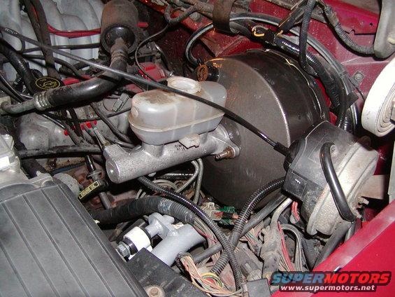 Engine bay showing brake booster, master cylinder, and various hoses and wires