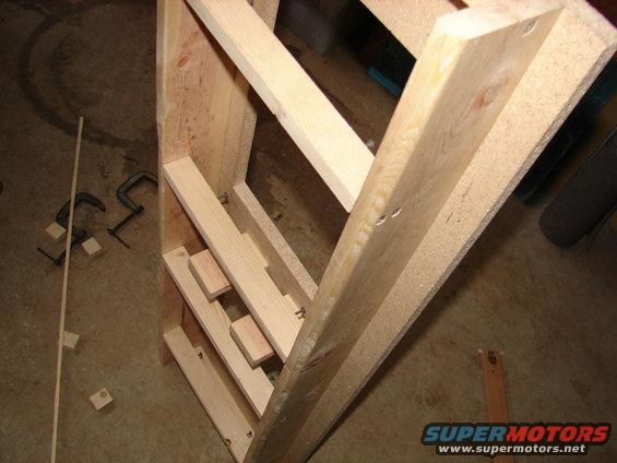 Wooden shelves being built with clamps and wood pieces on the floor