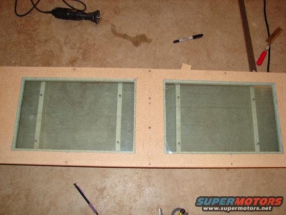 Wooden speaker enclosure with two glass panels, screws, and a marker
