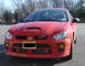 2005 Dodge SRT-4 - Front view of a red 2005 Dodge SRT-4 with a hood scoop and yellow fog lights.