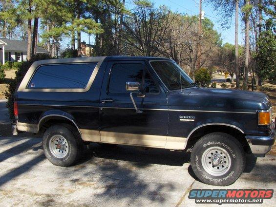 Side view of a dark blue and tan 1991 Ford Bronco parked on a driveway