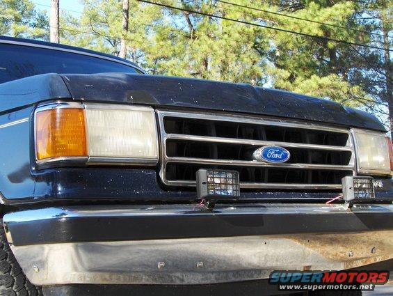 Front view of a 1991 Ford Bronco's grille with Ford logo and aftermarket lights