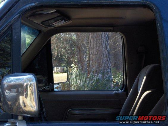 Interior view of a vehicle door and seat with a chrome side mirror