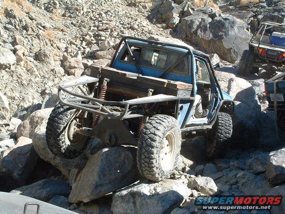 Blue off-road buggy with roll cage navigating rocky terrain