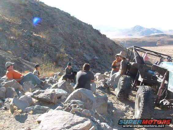 People gathered around a modified off-road buggy on a rocky hillside