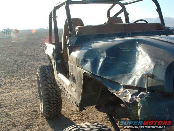 Damaged 1994 Jeep YJ with dented fender and hood, parked on dirt