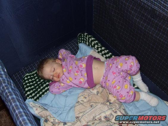 Baby sleeping in a crib wearing pajamas and socks