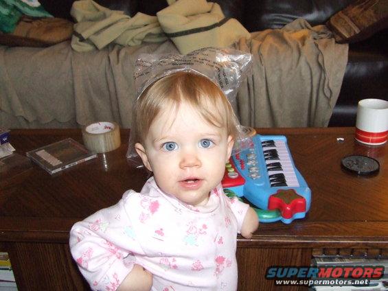 Baby with blue eyes and blonde hair sits at a wooden table with a toy piano