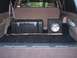 1996 Ford Bronco - The cargo area of a 1996 Ford Bronco contains a subwoofer, a toolbox, and a stick.