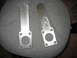 1992 Ford Mustang - Two metal brackets are shown, one with markings, resting on a textured surface.