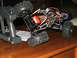 1996 Ford Bronco - An RC rock crawler sits on a wooden surface with its remote control nearby, showing its intricate suspension and electronics.