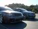 1994 Ford Probe - Two Audi sedans are parked in a lot under a bright sun, with a hillside in the background.