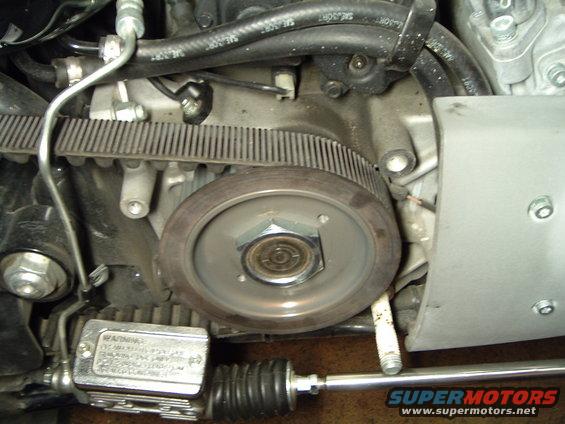 Motorcycle engine's drive belt and pulley system, with a metal reservoir and black bellows